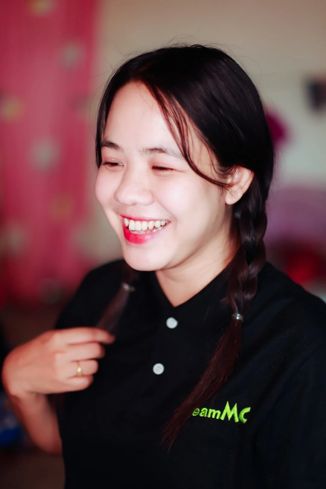 A smiling housekeeper is placing pillows on a sofa in a well-lit living room.